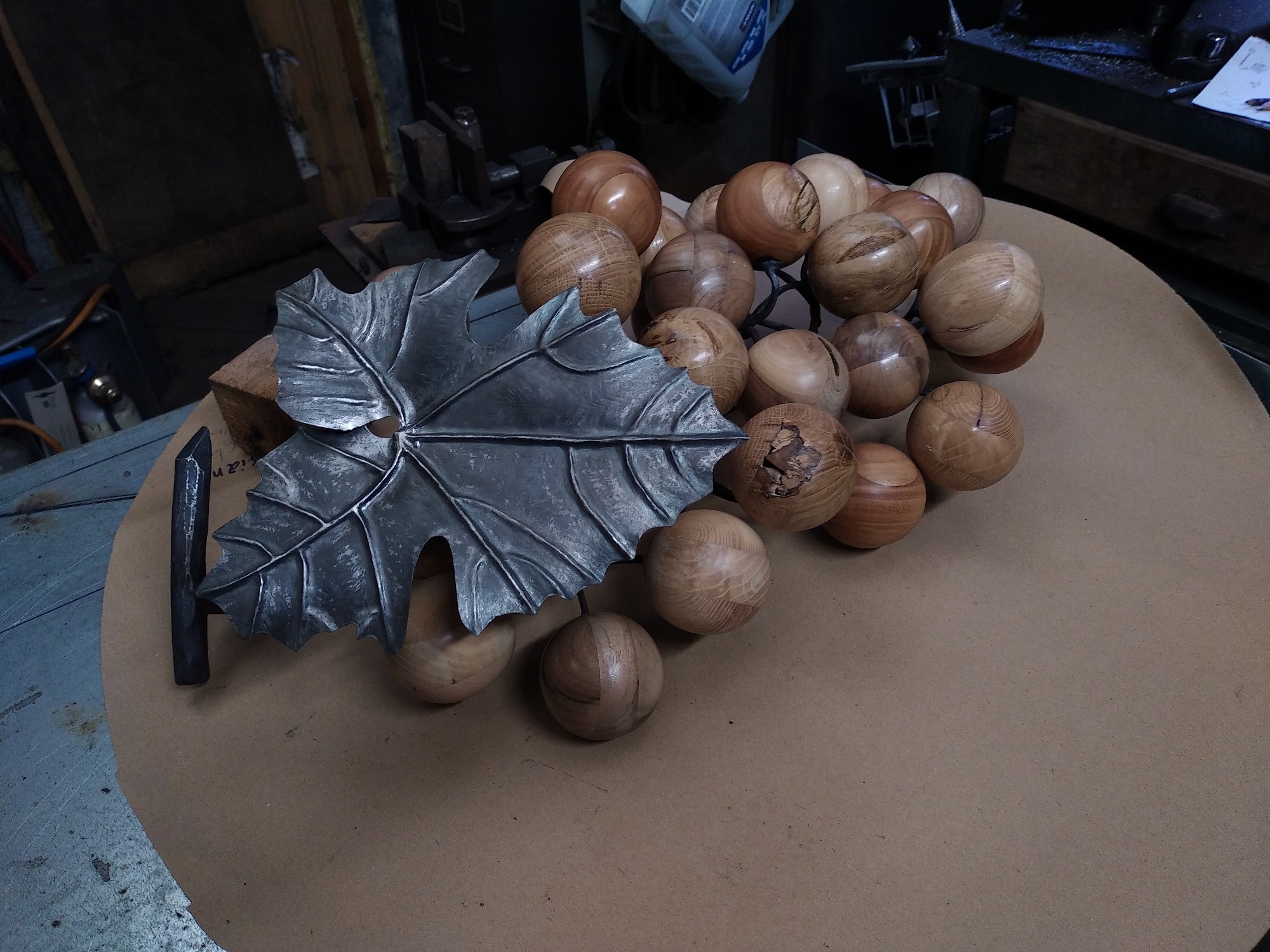 sculpture d'une grappe de raisin. Rafle et feuille en fer forgé et repoussé, grains en bois tourné (merisier, frêne, chêne et noyer)