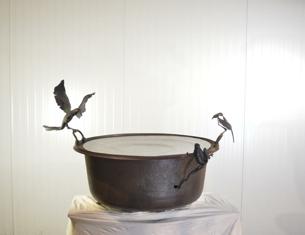 Sculpture d'oiseaux et d'une grenouille posés sur un bassin en fonte recouvert d'une coupe en acier inox martelé.
